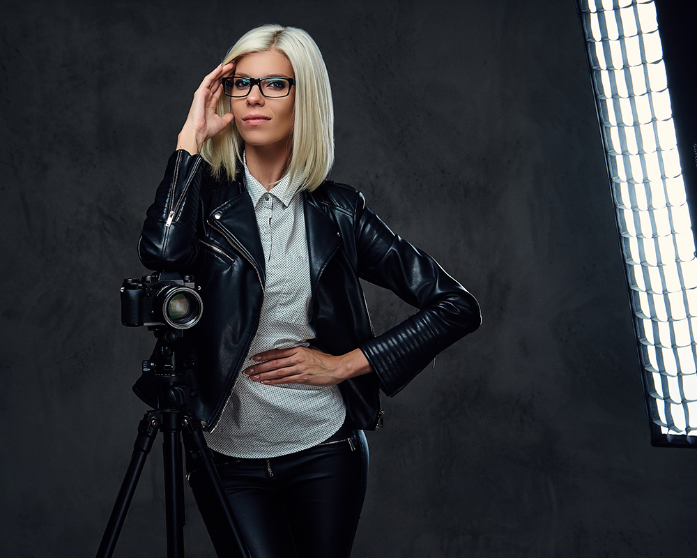 Modelo de estudio apoyada en la cámara de fotos. Vestida con pantalón y cazadora de cuero.