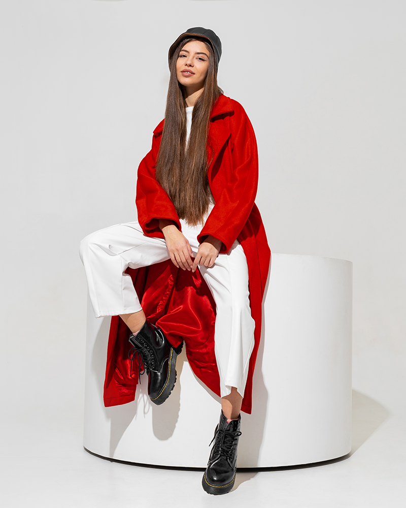 Modelo con pantalón blanco y abrigo rojo.