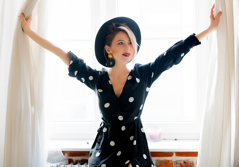 Modelo con vestido de lunares y sombrero negro.